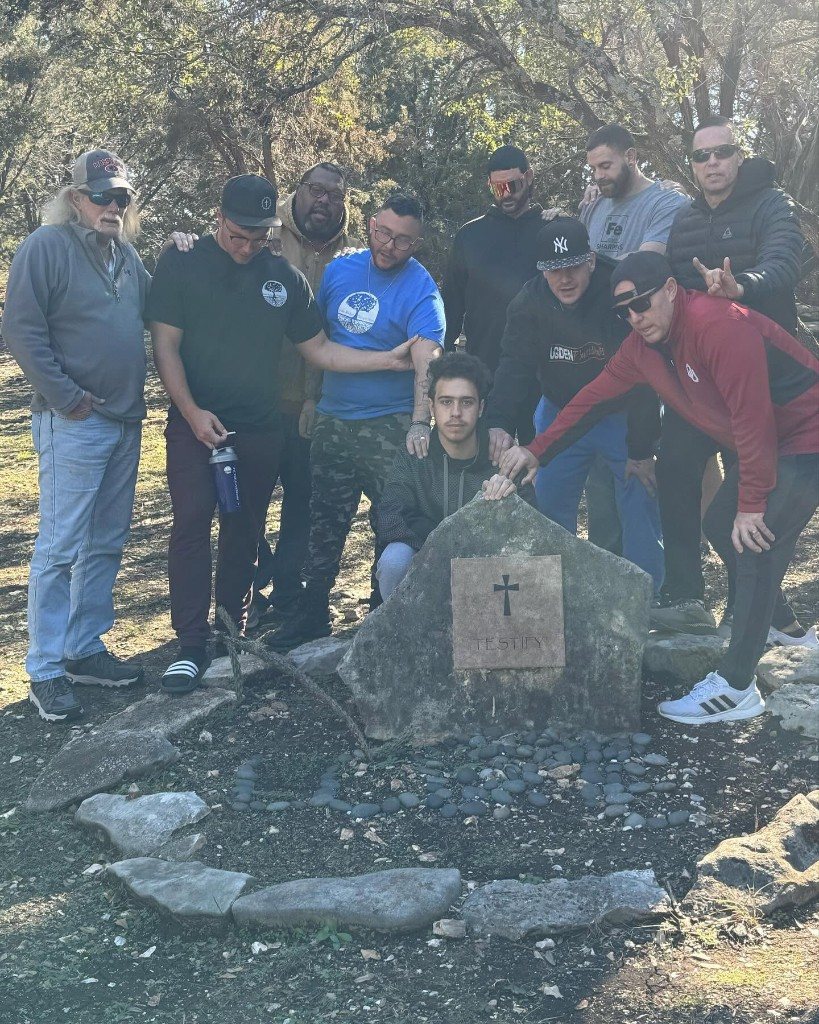 Men gathered at the Testify stone with Love spelled in stones
